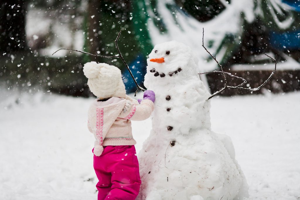 Девочка лепит снеговика