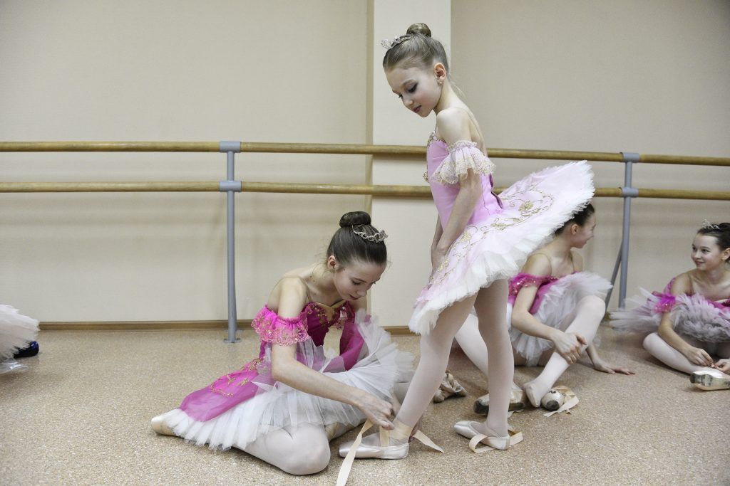 15 марта 2020 года. Юная балерина Елизавета Клокова (слева) помогает завязать ленты на пуантах своей подруге Елизавете Соловьевой перед занятием. Фото: Пелагия Замятина