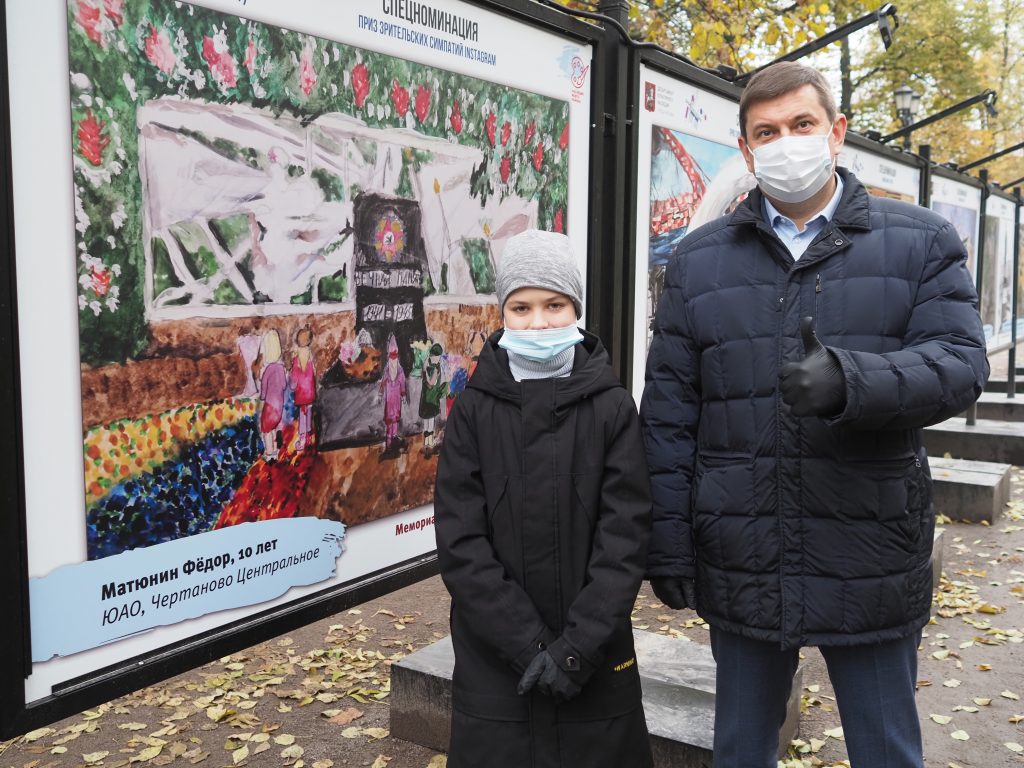 Федя Матюнин и руководитель Департамента культурного наследия Алексей Емельянов на открытии выставки на Гоголевском бульваре. На картине юного художника — мемориал Победы в парке 30-летия Победы в Чертанове Центральном. Фото: Пелагия Замятина